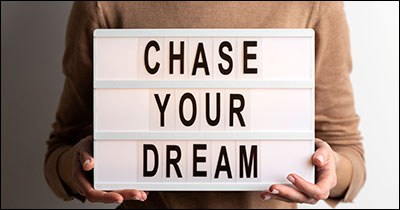Hands hold a board that says Chase Your Dreams